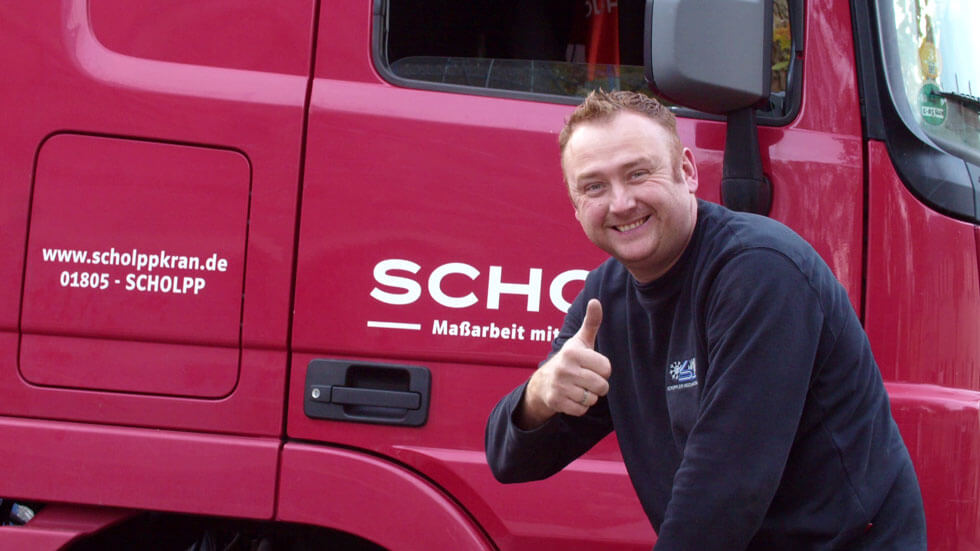 Arbeiter lacht in Kamera und zeigt Daumen nach oben