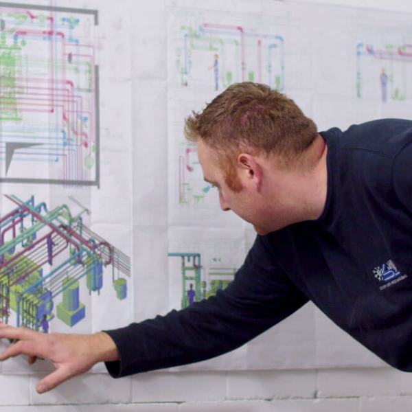 Arbeiter prüft auf Plänen die Installation der Wärmeanlage