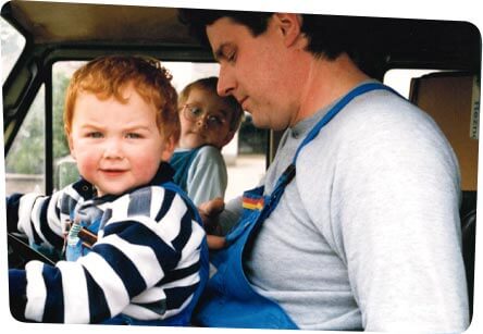 Handwerker mit Kindern Mann mit seinen Kindern sitzt in einem stehenden Auto, während ein Kind den Lenker mit seinen Händen hält