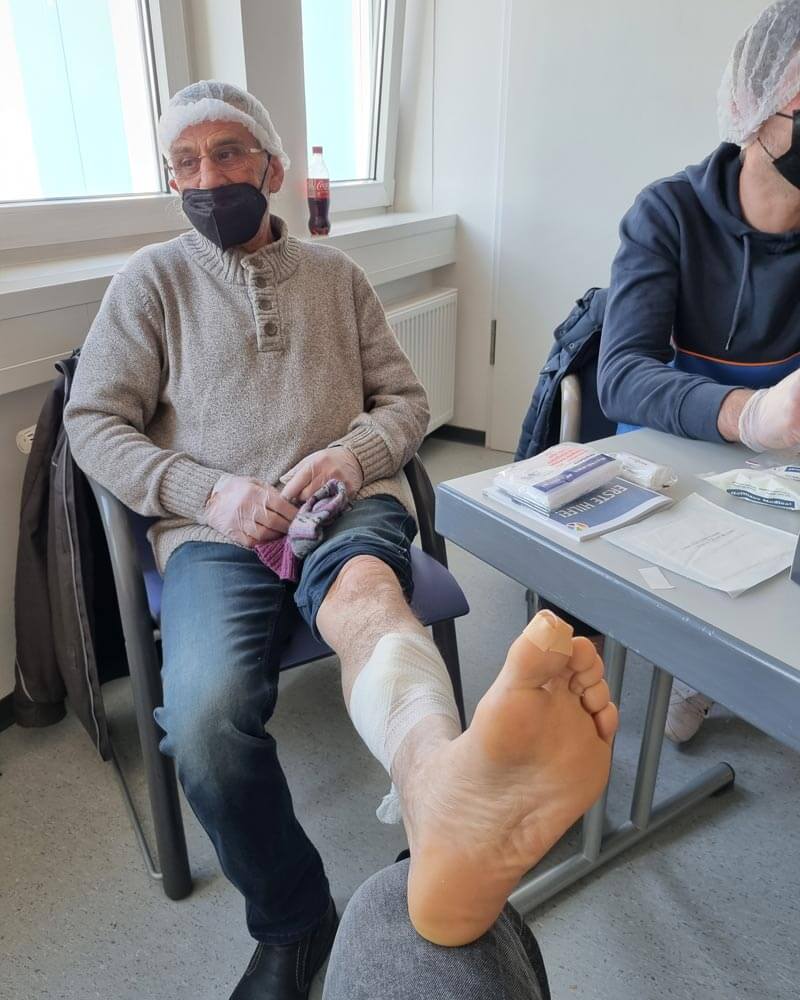 Mann sitzt auf einem Stuhl, während der Fuß versorgt wird