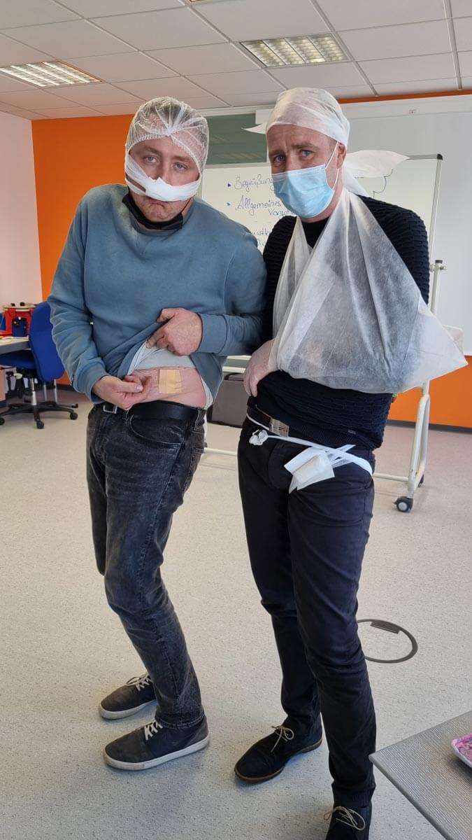 2 Mitarbeiter mit Verbänden posieren vor Kamera