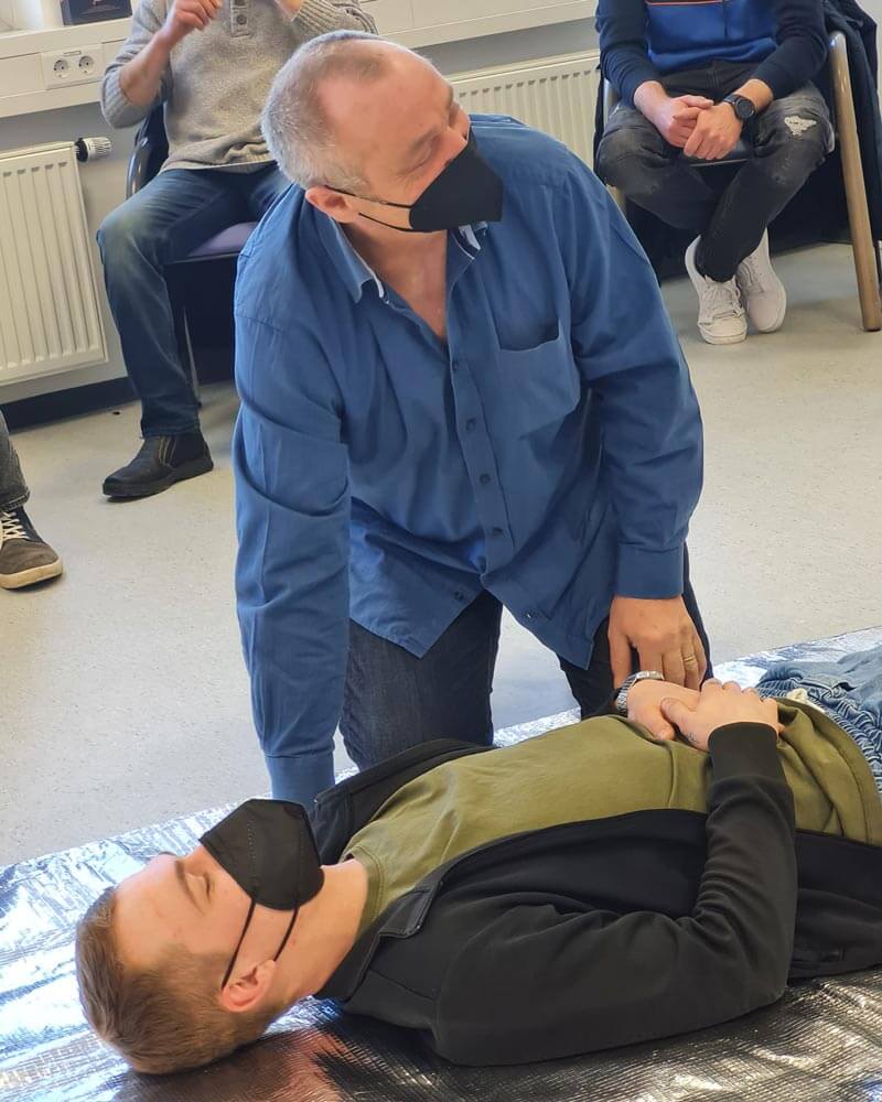 Mitarbeiter versorgt einen Mann, der auf einer Folie liegt