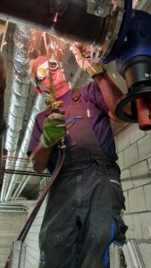 Mann schweißt Rohre zusammen