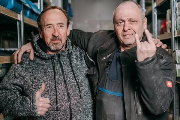 Teamfoto: 2 Mitarbeiter der Firma. Ein Mitarbeiter legt den Arm auf die Schulter des Kollegen.