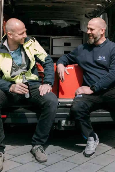 2 Mitarbeiter sitzen im offenen Fahrzeug und unterhalten sich