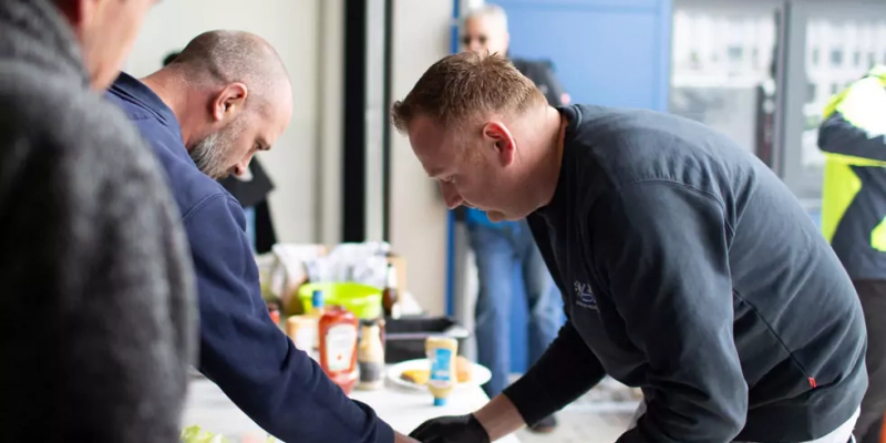 Teammitglieder bei einem Firmenevent bereiten Burger zu